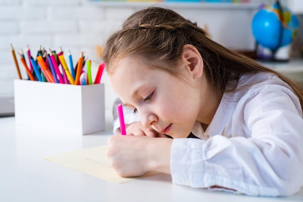Criança feliz e alegre desenhando o conceito de criatividade Criança bonita desenhando usando caneta de feltro enquanto está sentado à mesa
