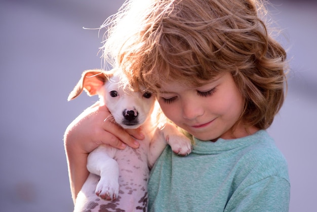 Criança feliz e cachorro a abraça com ternura sorrindo Garotinho abraçando cachorrinhos Feche o espaço da cópia Menino bonito fecha os olhos de prazer carrega cachorrinho