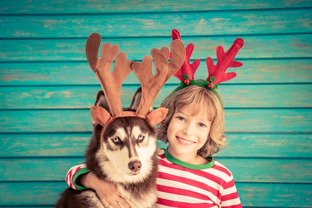 Criança feliz e cachorro na véspera de natal criança e animal de estimação vestido com chapéu de papai noel bebê se divertindo com h