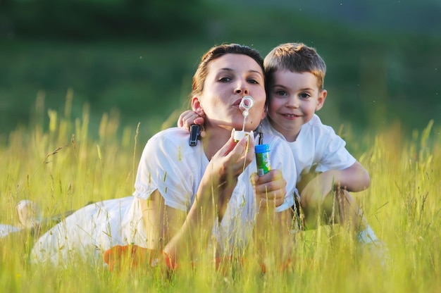 criança feliz e mulher ao ar livre brincando com bolha de sabão no Prado