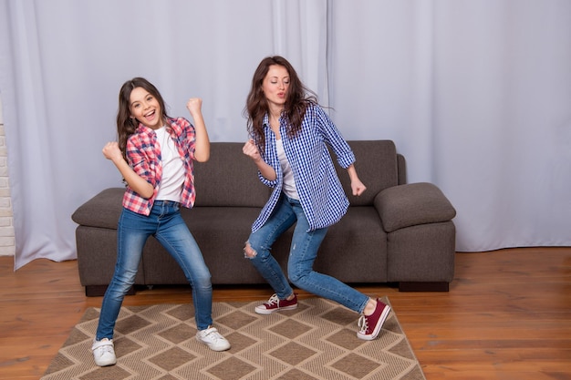 Criança feliz e mulher dançam juntos se divertindo em família em casa dançando