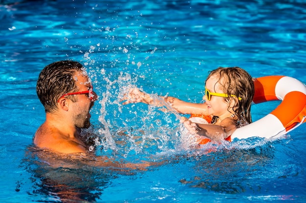 Foto criança feliz e pai brincando na piscina