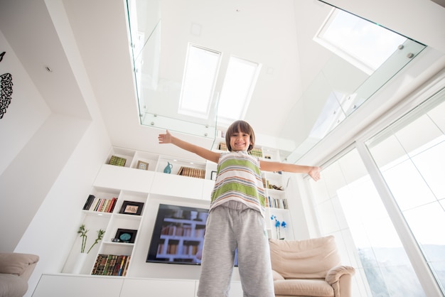 Foto criança feliz em casa com as mãos para cima