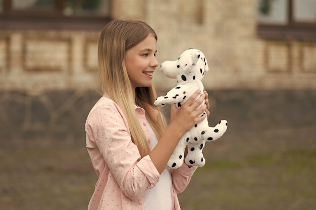 Criança feliz em casual brincando com brinquedo de cachorro de pelúcia ao ar livre infância