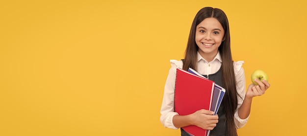 Criança feliz em idade escolar segura maçã e livros conhecimento de fundo amarelo Banner de estudante de escola Retrato de aluno de colegial com espaço de cópia