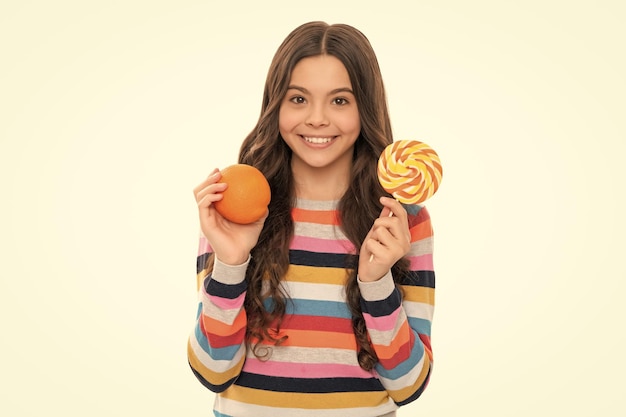 Criança feliz em suéter colorido com fruta laranja e pirulito isolado na infância saudável branca