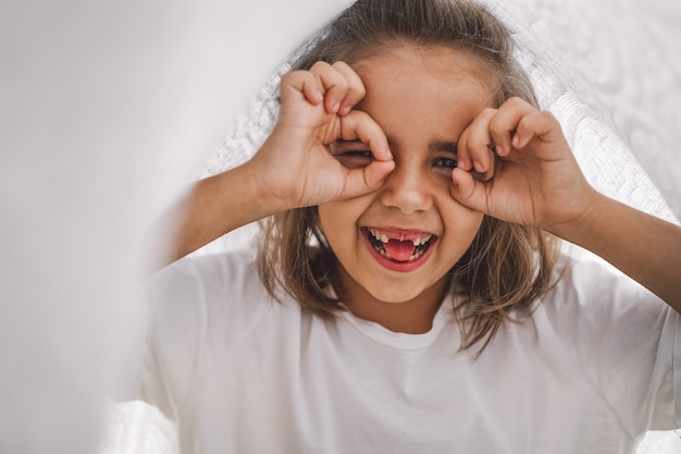 Criança Feliz. Garota engraçada brincando com um cobertor. Menina criança sorridente. Criança alegre ao ar livre na natureza