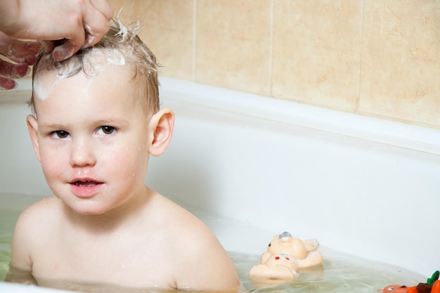 Criança feliz garotinha toma banho em um banho de espuma lava o rosto o conceito de higiene infantil alegria espirra risos divirta-se estilo de vida familiar