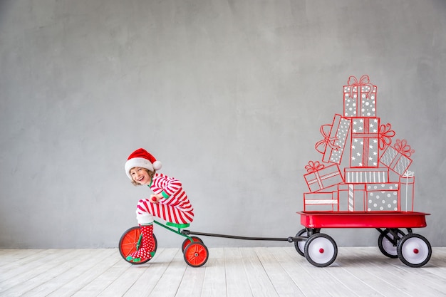 Criança feliz na época do Natal. Garoto engraçado brincando em casa