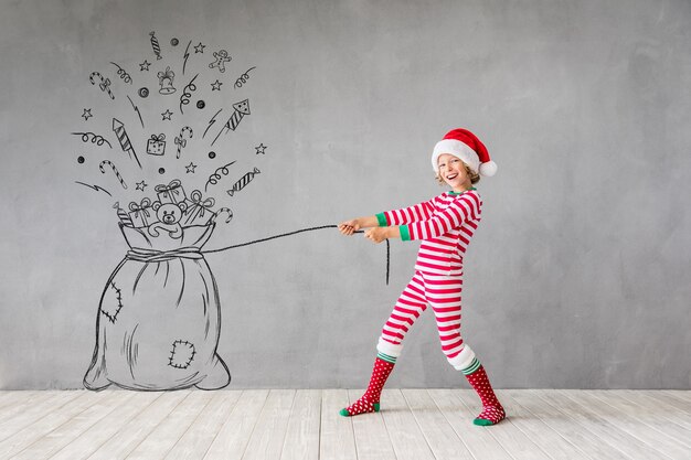 Criança feliz na época do Natal. Garoto engraçado brincando em casa