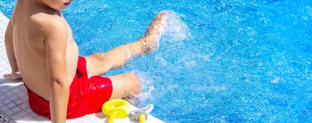 Criança feliz na piscina brincando com uma pistola de água.