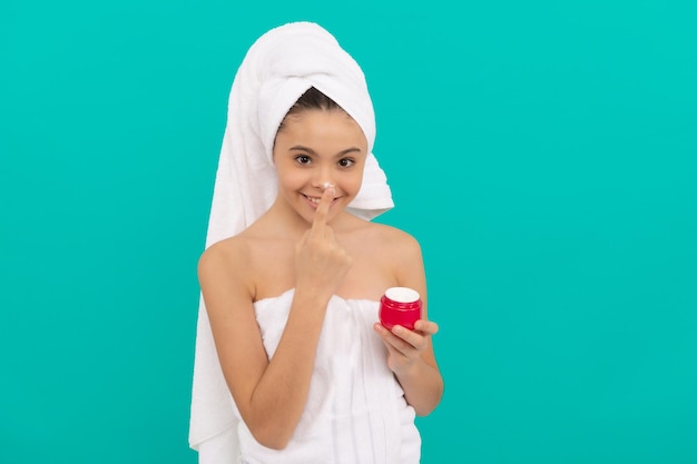 Criança feliz na torre de banho aplicando cosmético de creme facial