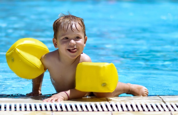 Criança feliz nadando na piscina com asas