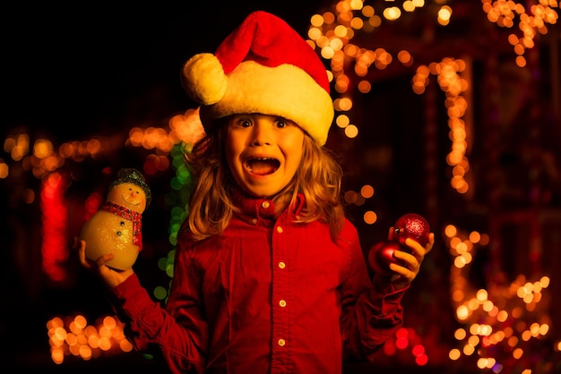 Criança feliz no jogo de chapéu de Papai Noel na frente de uma casa noturna