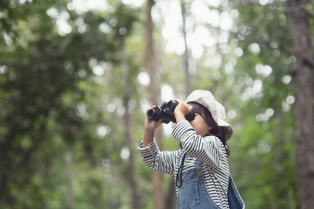 Criança feliz olhando para o futuro. Criança sorridente com o binóculo. Conceito de viagens e aventura. Liberdade, férias