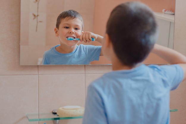 Criança feliz ou criança escovando os dentes no banheiro.