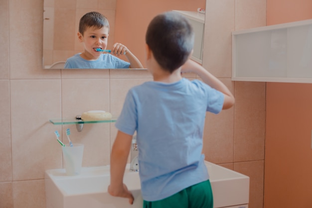 Criança feliz ou criança escovar os dentes no banheiro.