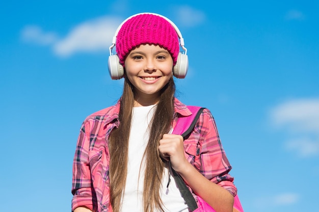 Criança feliz ouve música em fones de ouvido modernos céu ensolarado ao ar livre educação musical