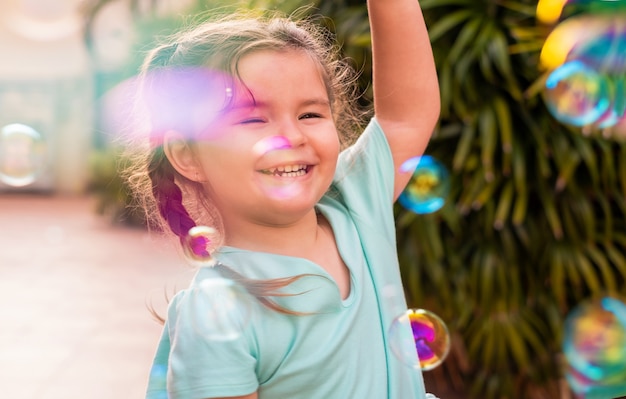 Criança feliz pegando bolhas de sabão