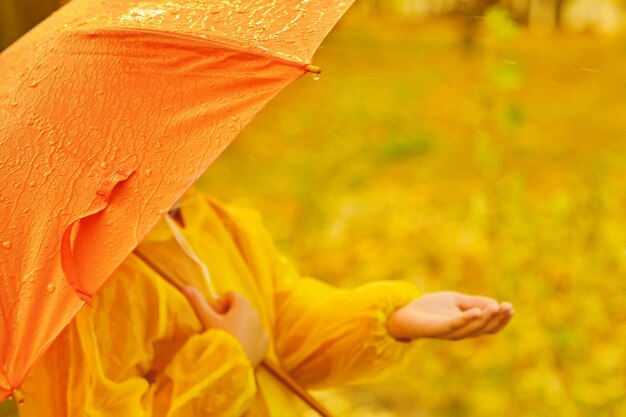 Criança feliz pegando gotas de chuva no parque outono