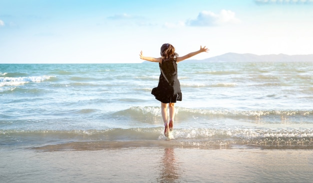 Criança feliz pulando na praia no verão