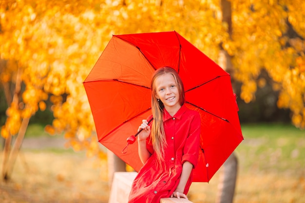 Criança feliz rindo sob o guarda-chuva vermelho