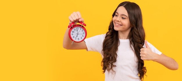 Criança feliz segura despertador retrô mostrando tempo polegar para cima Criança adolescente com alarme de relógio horizontal