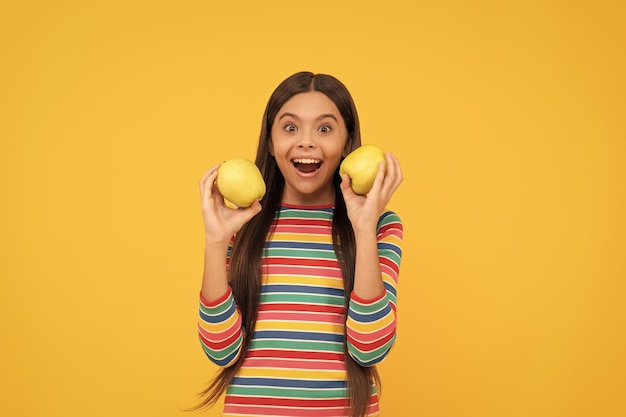 Criança feliz segura maçãs para dentes saudáveis sorriso de fundo amarelo