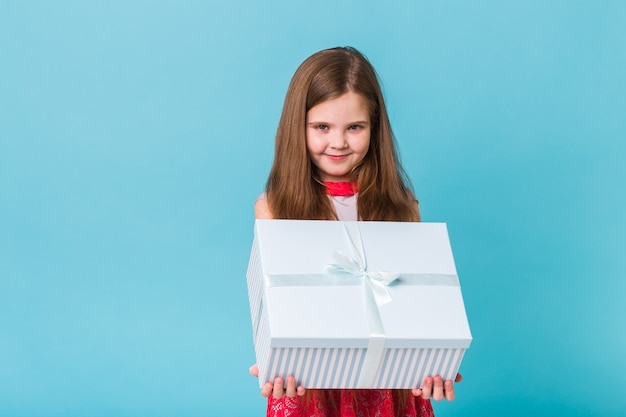 Criança feliz segurando presentes de aniversário em uma parede azul.