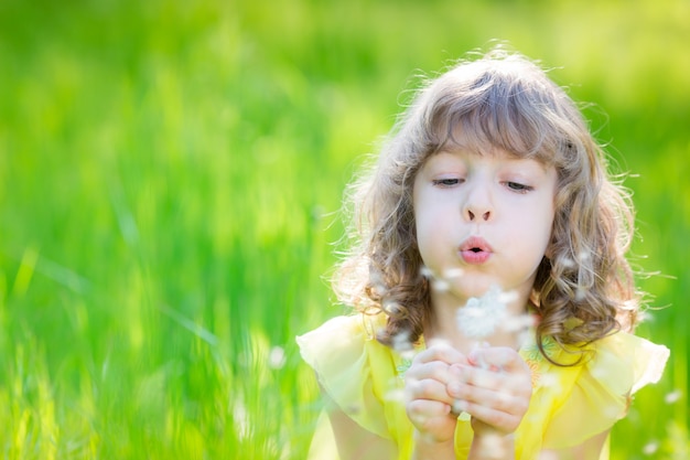 criança feliz soprando flor dente de leão ao ar livre se divertindo no parque primavera