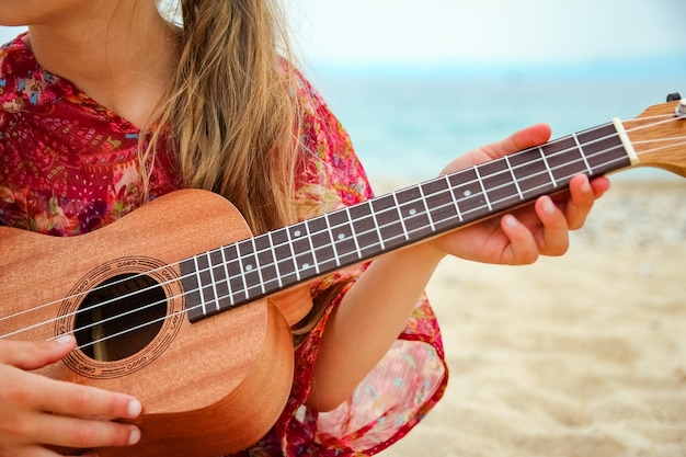 Criança feliz tocando guitarra à beira-mar da Grécia no fundo da natureza