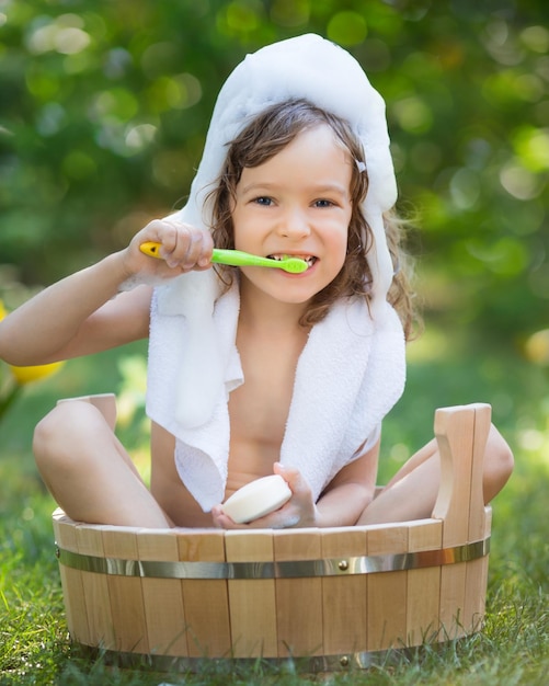 Criança feliz tomando banho ao ar livre na grama verde no jardim primavera