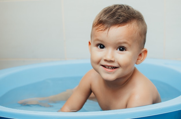 Criança feliz, um menino toma banho muito fofo