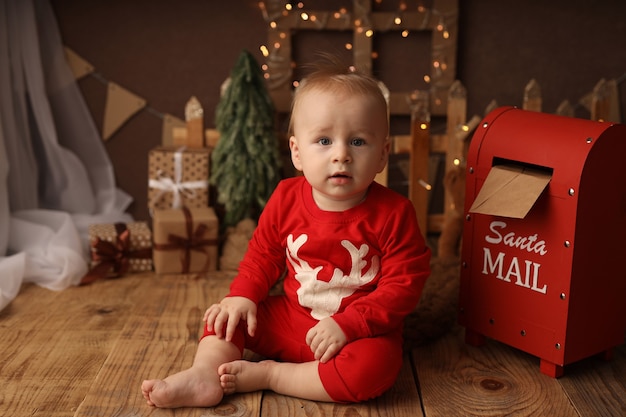 criança fofa de pijama de ano novo joga uma carta para o Papai Noel na caixa de correio