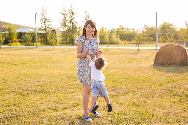 Criança fofa e alegre com a mãe brincando ao ar livre no parque