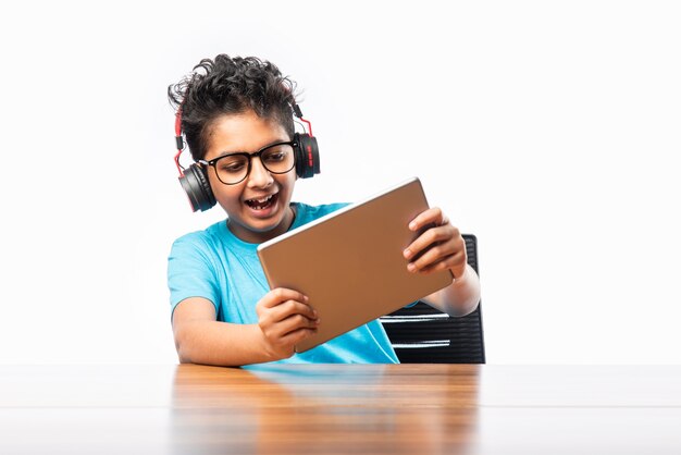 Criança indiana asiática brincando ou estudando em um computador tablet, sem fio