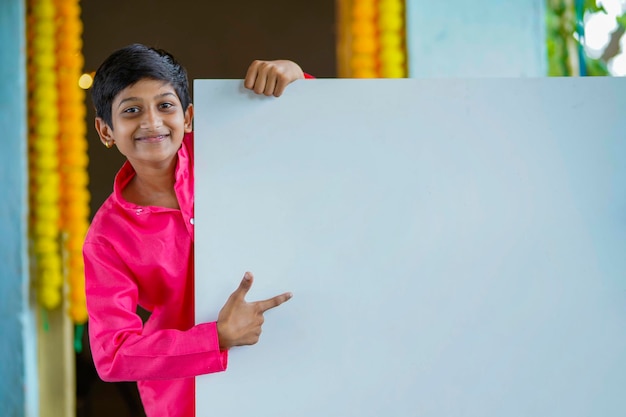 Criança indiana com roupas tradicionais e quadro branco.