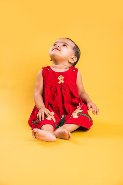 Criança indiana ou asiática, bebê ou bebê brincando com brinquedos ou blocos enquanto está deitado ou sentado isolado sobre um fundo brilhante ou colorido