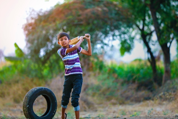 Criança indiana rural jogando críquete