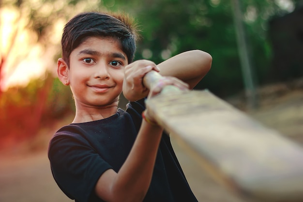 Foto criança indiana rural jogando críquete