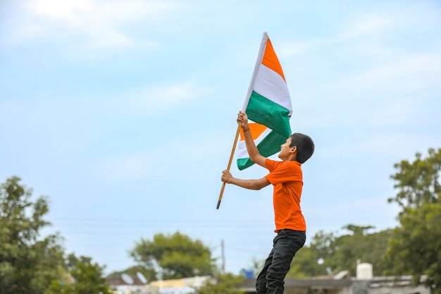 Foto criança indiana segurando, acenando ou correndo com a bandeira tricolor