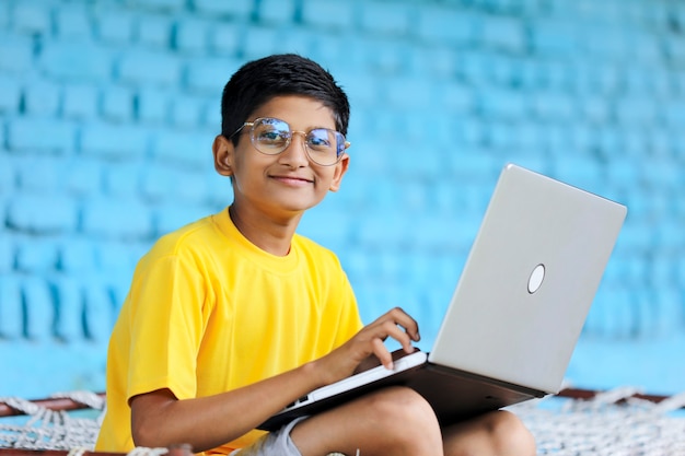 Criança indiana usando laptop em casa. participando de aulas online