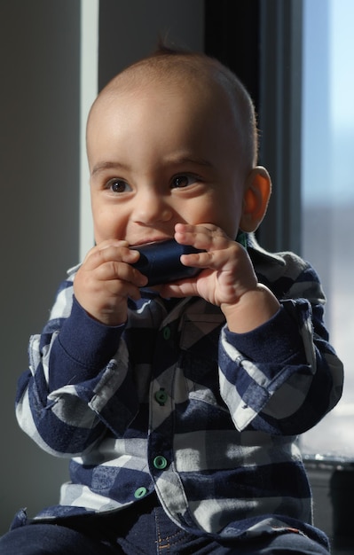 Criança infantil segurando uma caixa de metal e colocando-a na boca