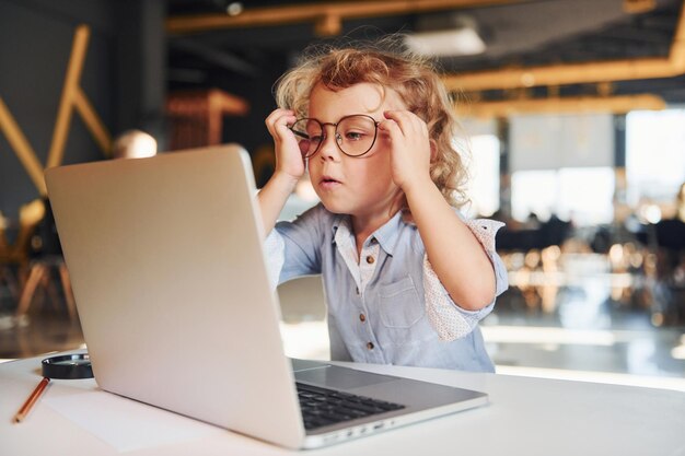 Criança inteligente em roupas casuais usando laptop para fins educacionais ou diversão