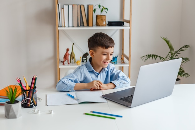 Criança inteligente fazendo lição de casa usando laptop e internet