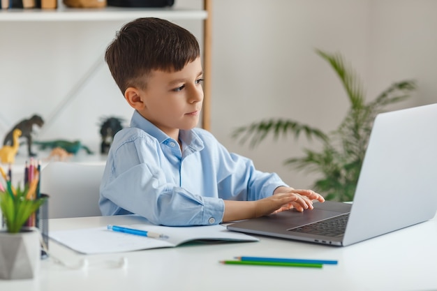 Criança inteligente fazendo lição de casa usando laptop e internet