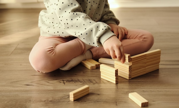 Criança joga um jogo de tabuleiro que cria a partir de blocos de tijolos de madeira jogos educativos para crianças