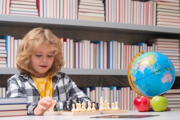 Criança joga xadrez na sala de aula criança jogando xadrez criança pensando perto do tabuleiro de xadrez aprendendo e crescendo