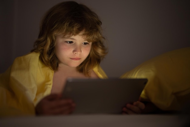 Criança jogando em um tablet digital criança usando tablet para jogos e aprendizagem on-line enquanto deitado no