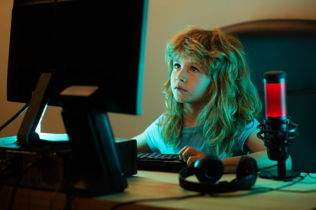 Criança jogando jogos de computador ou estudando no computador PC jogador infantil na iluminação de néon noturno pequeno hack